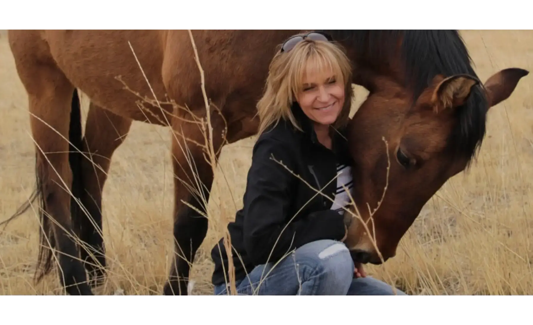 Sandi sitting beside a horse